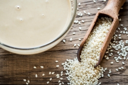 Bowl of techina next to a spoonful of sesame seeds